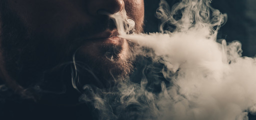 Man vaping e-cigarette with e-liquid. Vape concept