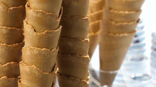 Empty ice cream cone stacks at the icecream parlor bar, kiosk or cafe against white background, tilt up shot, selective focus