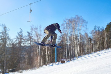 Portrait of young man performing snowboarding stunt flying high in air on mountain piste  at ski...