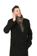 Fototapeta premium Young man talking on phone against white background. Ready for winter vacation