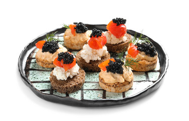Plate of delicious canapes with black caviar on white background