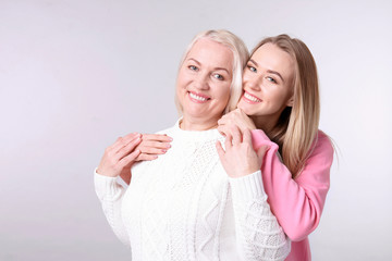 Young daughter and mother on light background