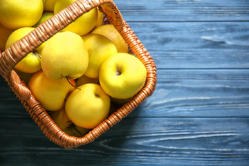 Basket with ripe yellow apples on wooden background