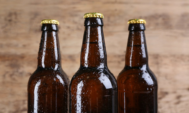 Fresh beer in glass bottles on wooden background, closeup
