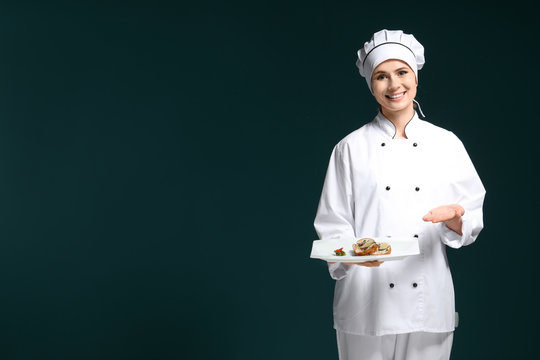 Female chef in uniform with tasty dish on dark background