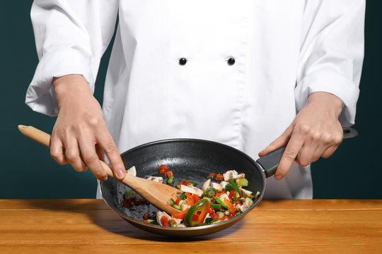 Female chef in uniform cooking tasty dish on table, closeup