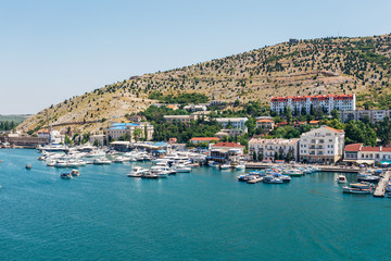 Fototapeta na wymiar Resort town. Boat parking and modern buildings on the Black Sea coast of the Balaklava bay, Crimea, Russia