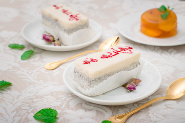 A fresh piece of coconut cream cake on a white plate with a whipped cream and peach jelly. White background. Top view