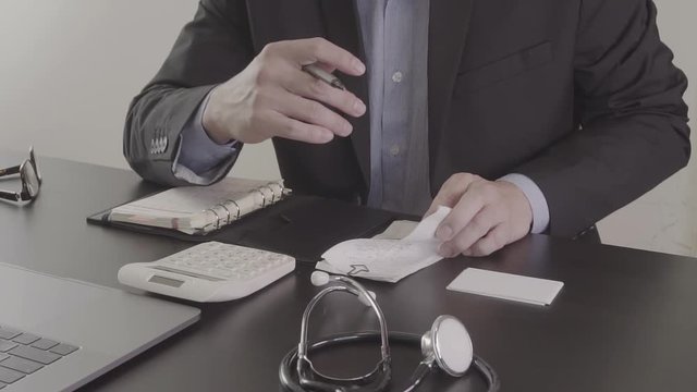 Healthcare costs and fees concept.Hand of smart doctor used a calculator for medical costs in modern hospital in slow motion
