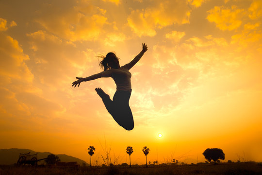 Silhouette of happy woman jumping over sunrise. Concept image for symbolic of successful, image made warmth tone.