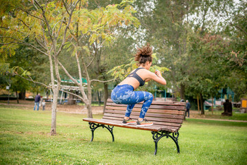 Female athlete doing squats on park bench