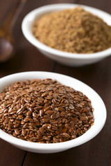 Whole brown flax seeds or linseeds and ground linseeds in small bowl, photographed on dark wood with natural light (Selective Focus, Focus one third into the image)