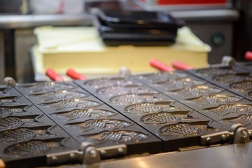 Close-up detail of multiple iron molds for making Taiyaki fish shaped red bean pastries. Canal City, Fukuoka, Japan. Travel and cuisine concept.