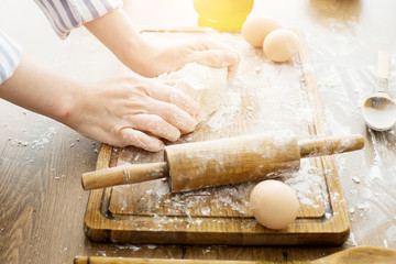 Female hands making dough on kitchen background