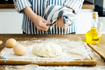 Female hands making dough on kitchen background