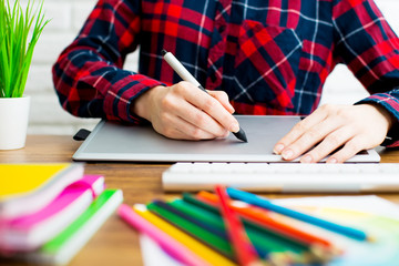 Young graphic designer woman using digital graphic tablet while working at office