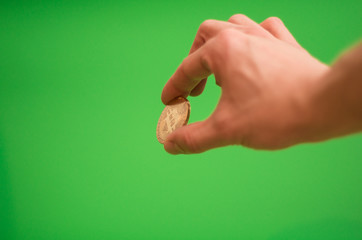 Fototapeta premium Man's hand holding golden Bitcoin cryptocurrency coin on green background - chroma key / blue box / green screen