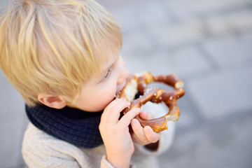 Little tourist eating traditional bavarian bread called pretzel