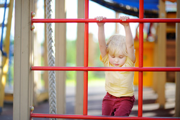 Fototapeta premium Little boy having fun on outdoor playground. Summer active sport leisure for kids