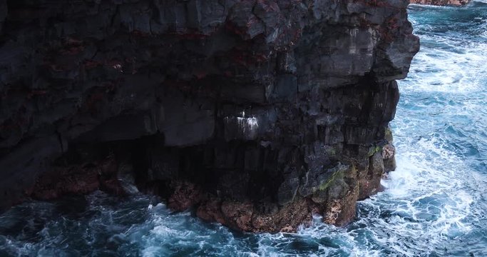 timelapse footage of the ocean swell crashing against black volcanic rock cliffs in the big island of hawaii in volcano national park on the coast