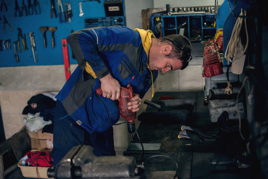 Mechanic using drill in workshop