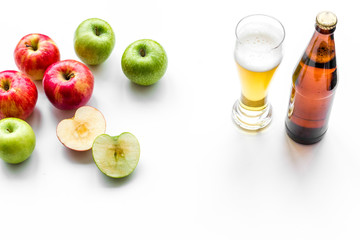 Apple cider poured into glass near bottle and apples. White background top view copy space