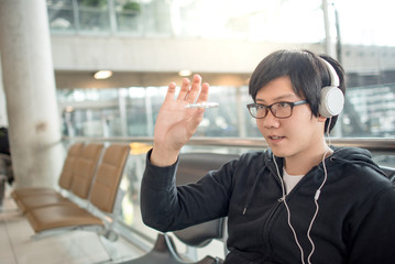 Young asian man playing spinner fidget while waiting for the airplane flight and listening to music...
