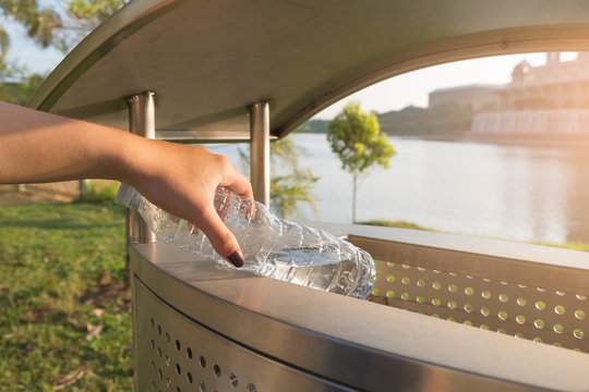 Close up hand throwing plastic bottle into a public trash