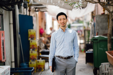 A portrait of a a young Asian Chinese businessman walking down an Asia's street alley. For the day,...