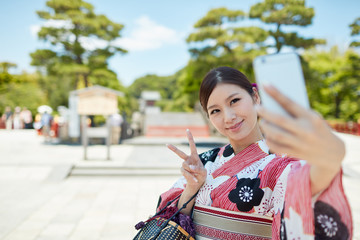 観光地で自撮りをする浴衣の女性