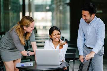 A picture of a diverse group of professionals working as one team on a new project. For their reference, they are using a laptop and they all wear professional outfits.