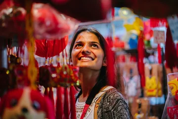 Stoff pro Meter A portrait of a young Indian lady wandering during the Chinese New Year festival in Asia at night on the market. When she looks around the trinkets hanging for the festivity, she looks fascinated. © Danon