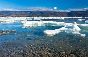 Sunny spring morning on Lake Baikal. White floes melt near the coast of Olkhon Island