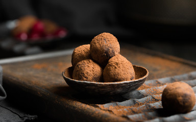 Chocolate truffle. Dark chocolate and cherry candy sprinkled with cocoa on a dark wooden background in rustic style. Atmospheric food photo.  Homemade fresh energy balls.