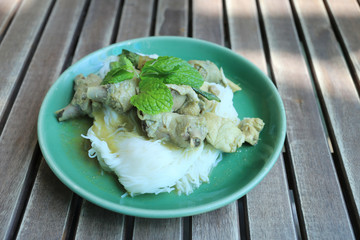 Thai Noodles with Chicken Curry (Kanom jeen) in a green dish.