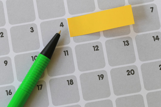 Green pen points to a four number of calendar and have blank yellow note paper.
