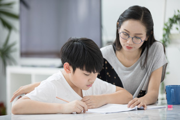 Asian boy with mother teaching and learning your homework at home