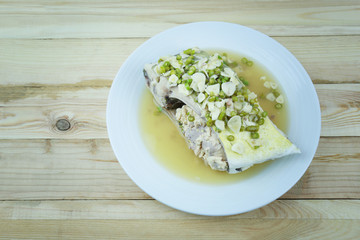 Golden toothless trevally fish with spicy and lemon of Thai foods in white dish on wooden.