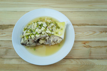 Golden toothless trevally fish with spicy and lemon of Thai foods in white dish on wooden.