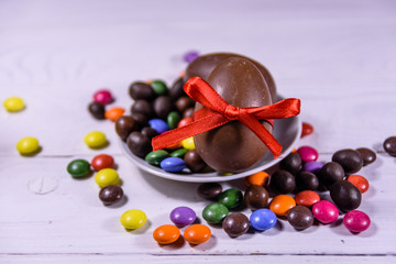 Chocolate easter eggs and multicolored candies on wooden table