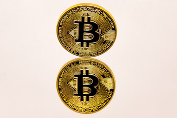 Conceptual representation of a gold bitcoin on a white mirror surface.