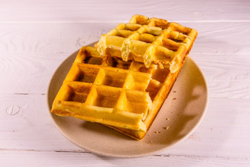 Ceramic plate with belgian waffles on wooden table