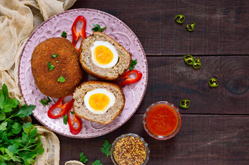 Large juicy cutlets stuffed with boiled egg on a dark wooden background. Scottish cutlet. The top view