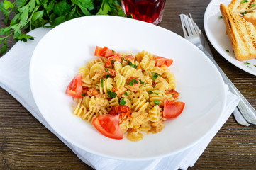 Warm salad with seafood in a white bowl on a wooden background. Pasta Radiatori with crayfish, shrimp, tomatoes, herbs and creamy garlic sauce.