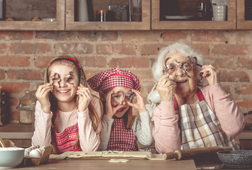 Granny with granddaughters looking at camera through cookie cutters