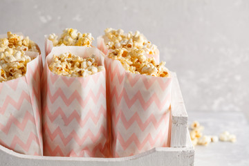 Golden caramel popcorn in pink paper bags in a white wooden box, copy space