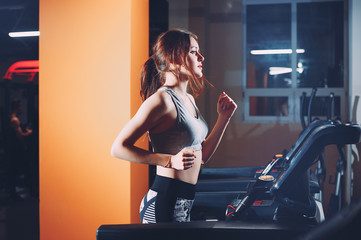 Obraz na płótnie Canvas rear view of a young woman running on treadmill
