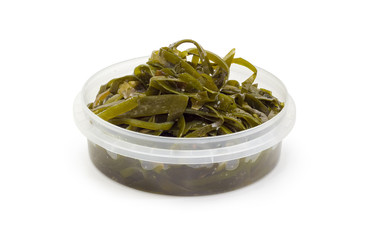 Salad of marinated laminaria with spices in round plastic container