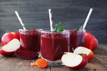 Beetroot smoothies with carrots and apples on a wooden table