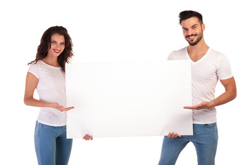 young casual couple recommending something on blank board